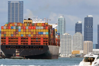 Container ship approaching cargo cranes at the Port of MiamiMiamiFlorida with downtown Miami skyline in the background.