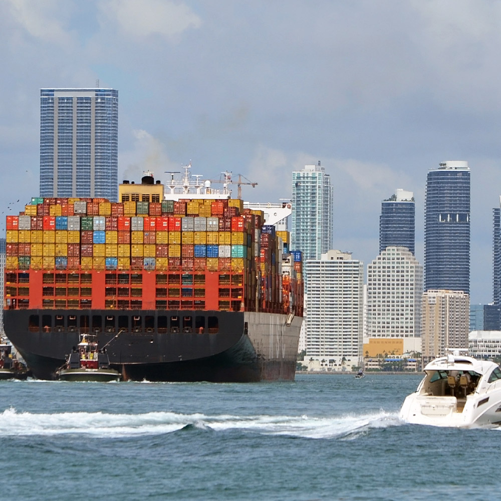 Container ship approaching cargo cranes at the Port of MiamiMiamiFlorida with downtown Miami skyline in the background.